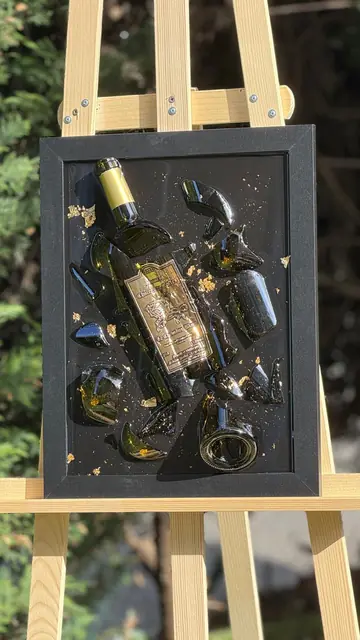 Bouteille de vin éclatée et reconstituée dans la résine avec feuille d'or, cadre noir sur chevalet